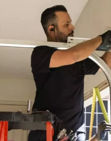 worker fixing a garage door of a house